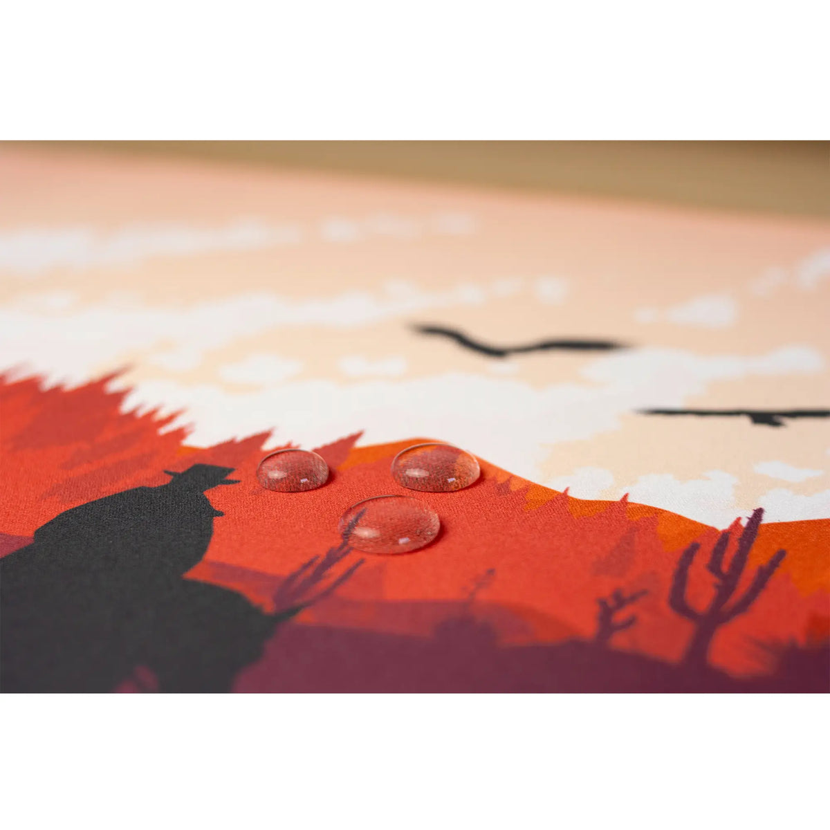 Clear water droplets on an arcaLoot Gaming Mousepad featuring a western desert landscape design. Sunset Wrangler.