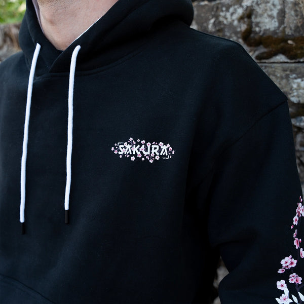ArcaLoot Sakura black hoodie with cherry blossom front logo, sleeve artwork, white hood lining and drawstrings.