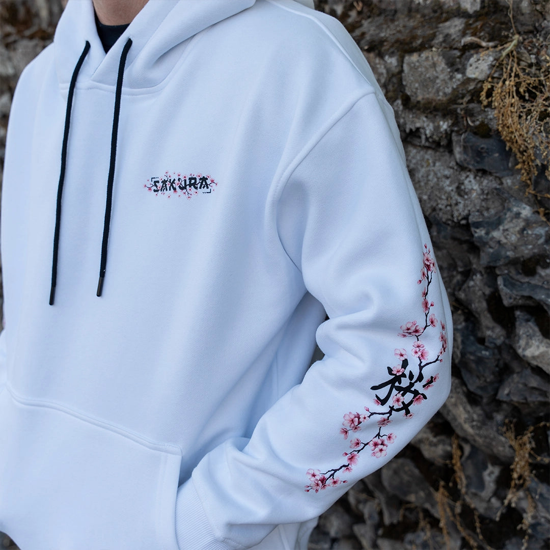 ArcaLoot Sakura white hoodie with cherry blossom front logo, sleeve artwork, black hood lining and drawstrings. Cherry Blossom sleeve design visible.