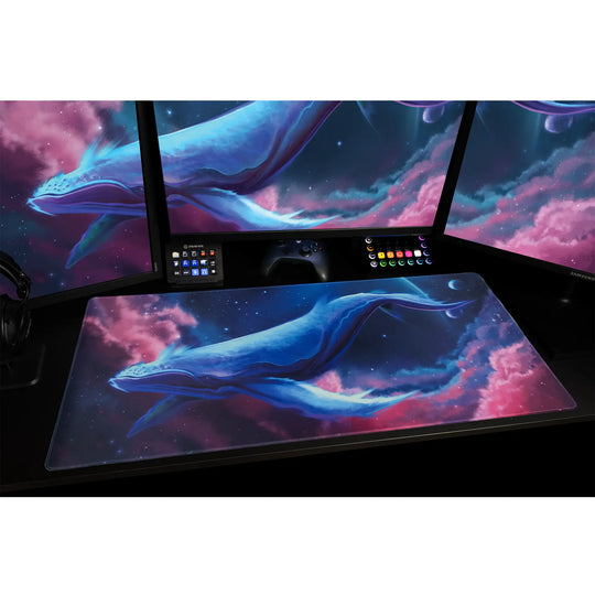 Large ArcaLoot gaming mousepad with a blue whale design against a colorful cosmic background on a black gaming desk. Cosmic Cetacean.