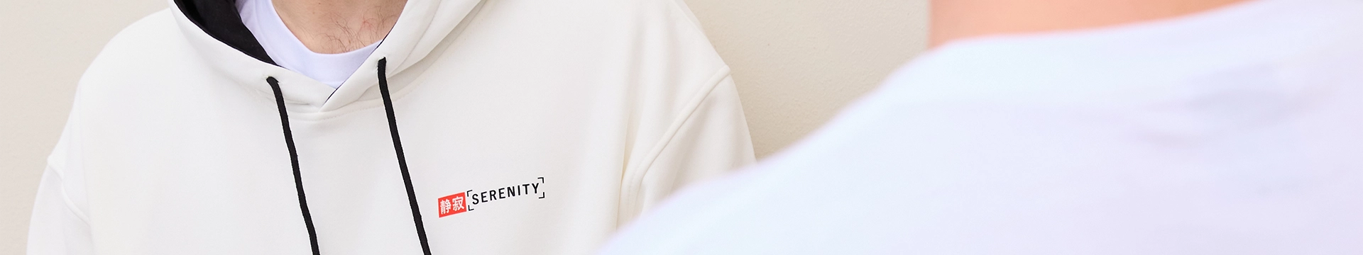 Close up of a person neck area in a white hoodie and a blurred out back of a person's collar in a white t-shirt. 
