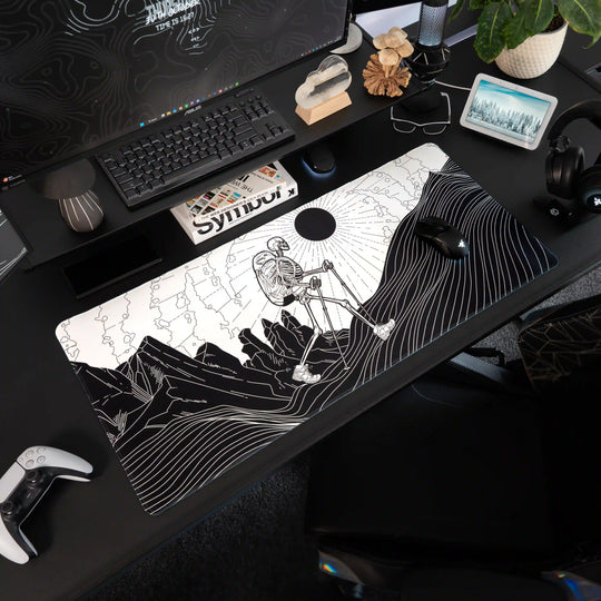 Large ArcaLoot gaming mousepad with a Skeleton figure hiking against a mountain landscape on a black gaming setup. Bare Boned Expedition. 