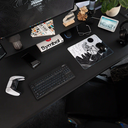 Small ArcaLoot gaming mousepad with a Skeleton figure hiking against a mountain landscape on a black gaming setup. Bare Boned Expedition. 