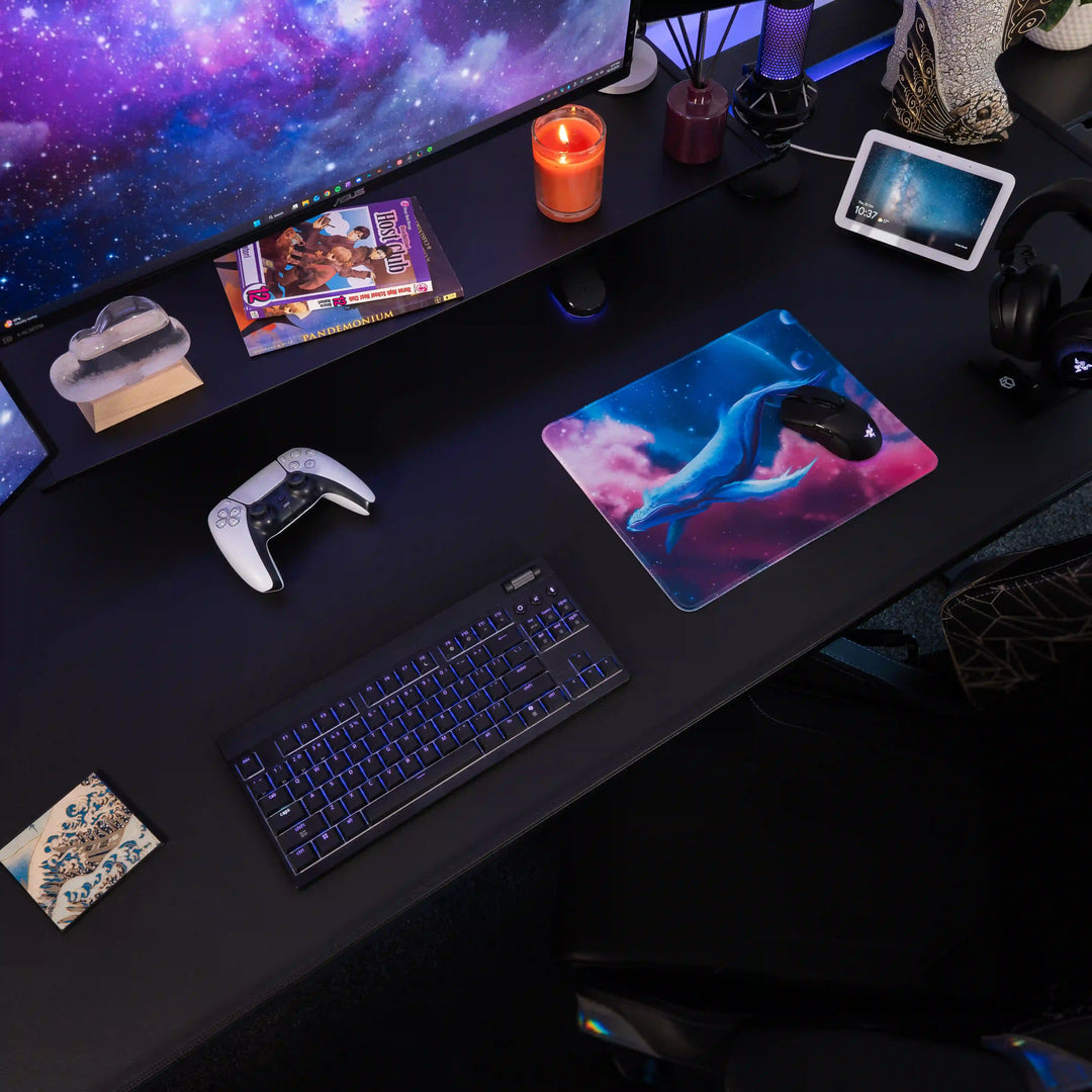 Small ArcaLoot gaming mousepad with a blue whale design against a colorful cosmic background on a black gaming desk. Cosmic Cetacean.