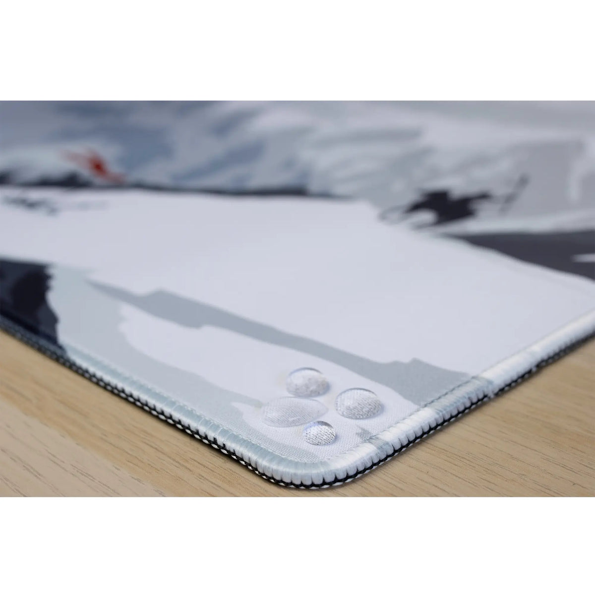 Clear water droplets on an ArcaLoot gaming mousepad featuring the stitched edges. Blade and Flame.